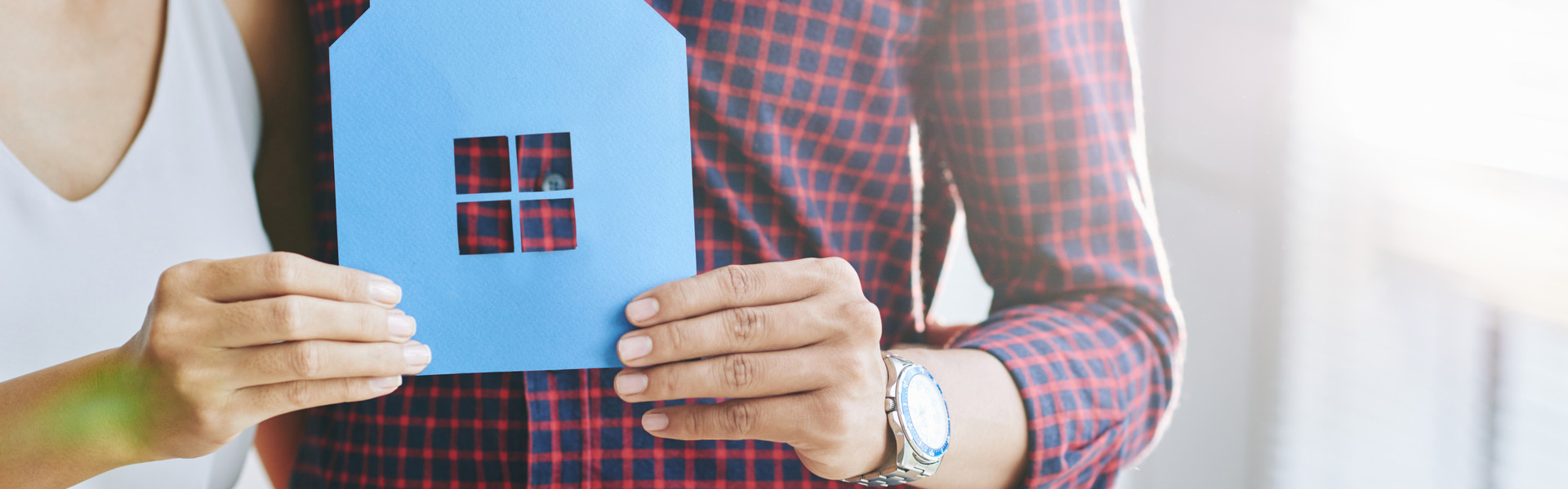 casually-dressed-unrecognizable-couple-hugging-posing-with-paper-cutout-house.jpg